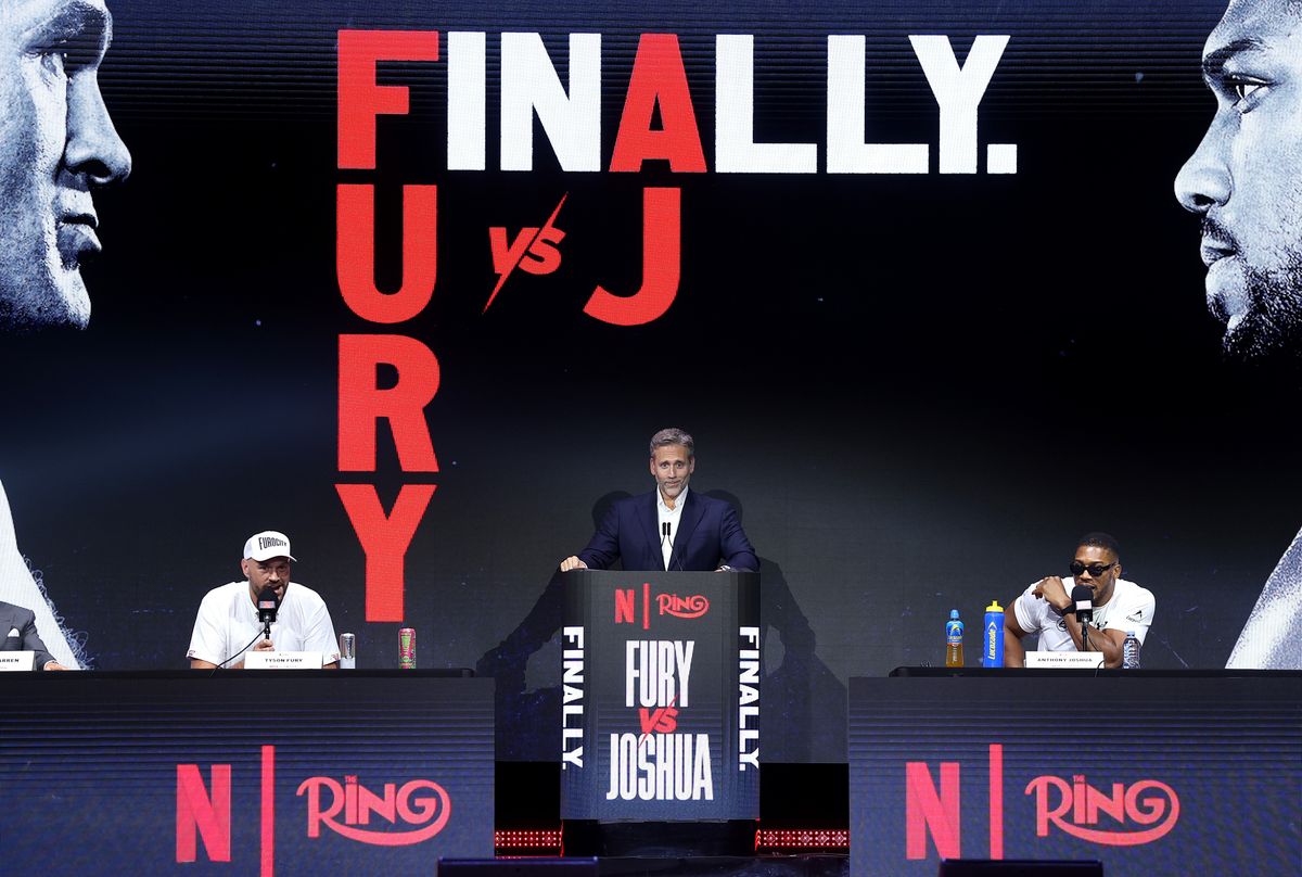 Tyson Fury, left, and Anthony Joshua, right, sit on either side of host Max Kellerman during Wednesday's press conference at Olympia in London. Tyson Fury, left, and Anthony Joshua, right, sit on either side of host Max Kellerman during Wednesday's press conference at Olympia in London.