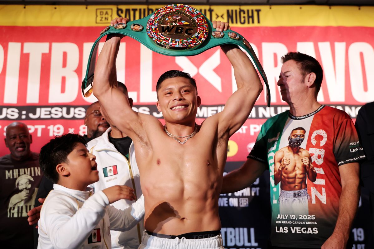 Isaac “Pitbull” Cruz with his son at his side, holds up his title for the crowd after making weight Friday. Isaac “Pitbull” Cruz with his son at his side, holds up his title for the crowd after making weight Friday.
