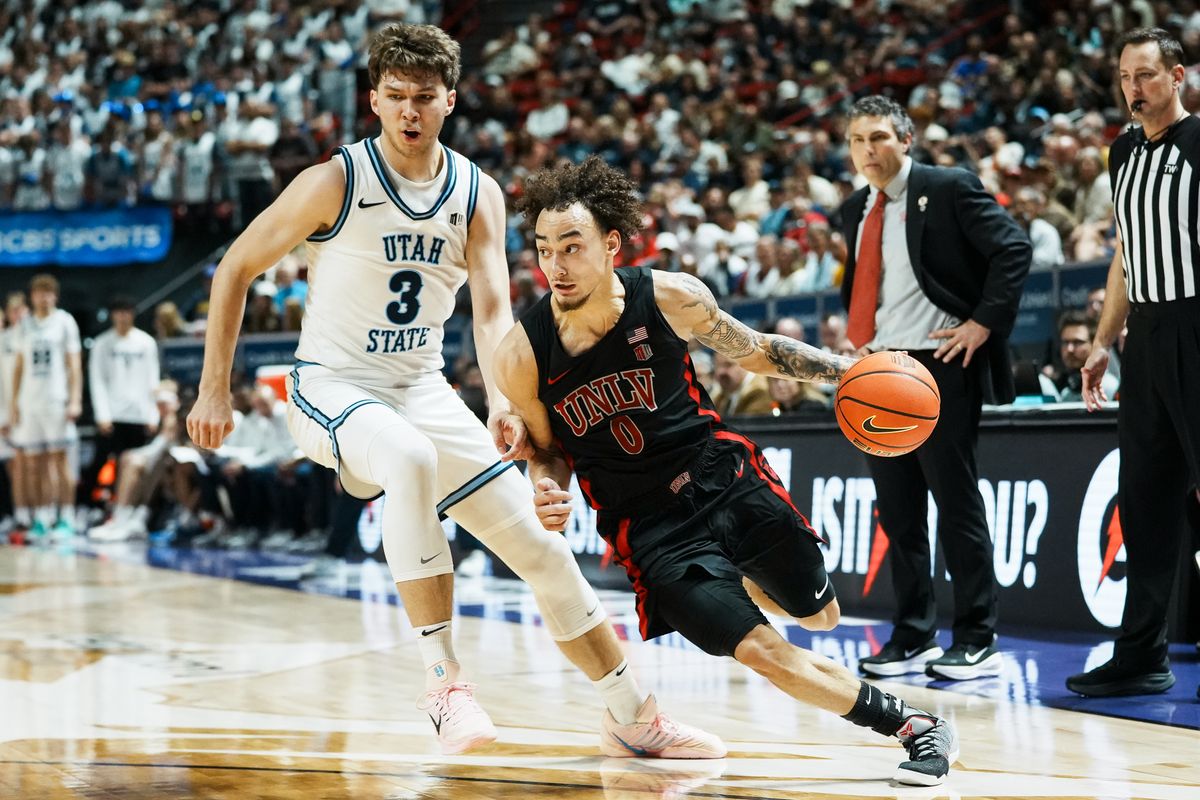 UNLV Runnin’ Rebels guard Dra Gibbs-Lawhorn (0) drives towards the basket while guarded by Utah State Tucker Anderson (3)  during the second round of a Mountain West Championship tournament game between the UNLV and Utah State on Thursday March 12, 2026 in Las Vegas, Nev.