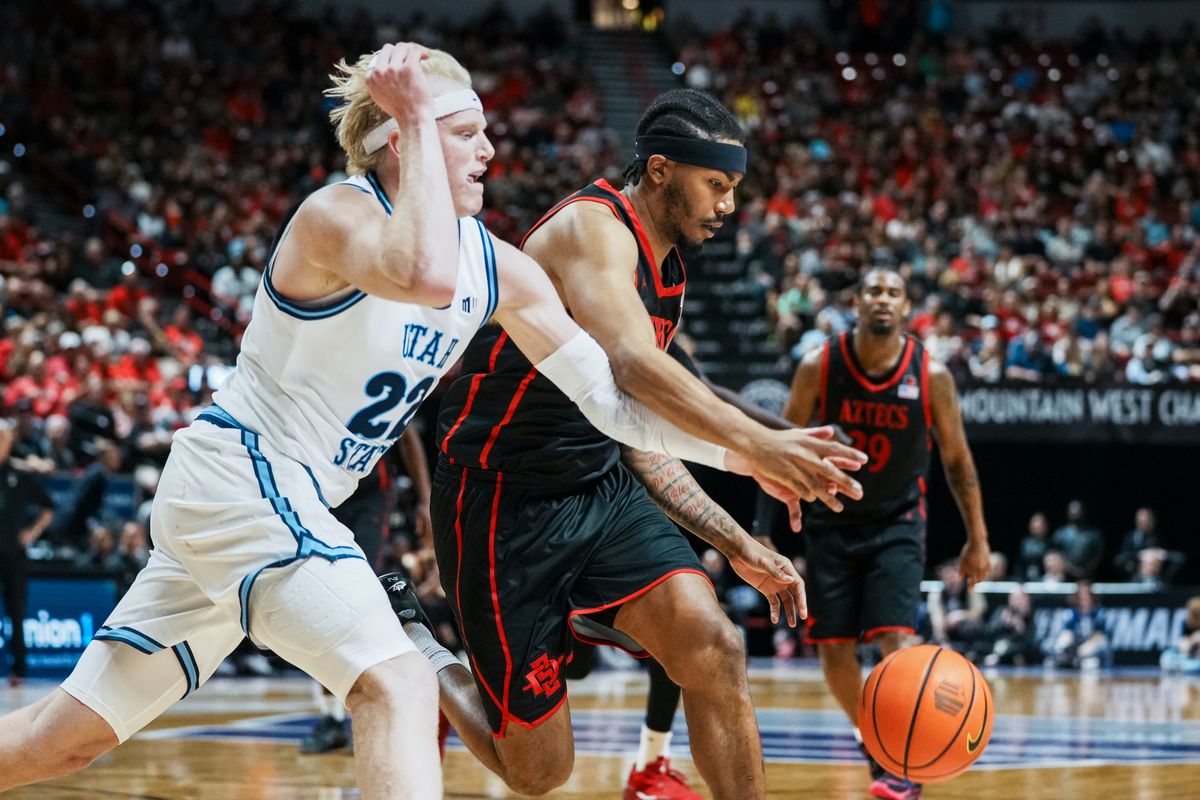 San Diego State guard Taj DeGourville (24) and Utah State forward Karson Templin (22) reach for control of the ball during final Mountain West Championship tournament game between San Diego State and Utah State on Saturday March 14, 2026 in Las Vegas, Nev.