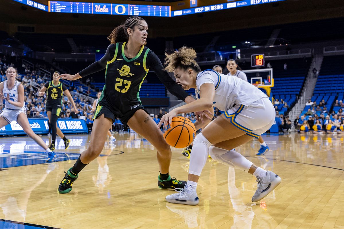 Guard Kiki Rice #1 of the UCLA Bruins takes an elbow to the face from forward Sarah Rambus #23 of the Oregon Ducks while handling the ball during an NCAA basketball game, Sunday December 7, 2025 in Los Angeles, Calif. 