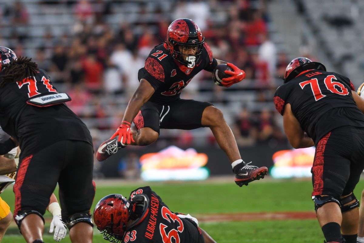 SDSU running back Byron Cardwell Jr. (21) leaps over a defender during an NCAA football game against the Wyoming Cowboys Saturday November 1, 2025 in San Diego, California. SDSU running back Byron Cardwell Jr. (21) leaps over a defender during an NCAA football game against the Wyoming Cowboys Saturday November 1, 2025 in San Diego, California.