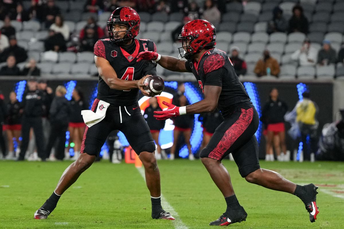 San Diego State University quarterback Jayden Denegal (4) hands the ball to San Diego State University running back Lucky Sutton (7) during an NCAA football game against Boise State, Saturday November 15, 2025 in San Diego, California.