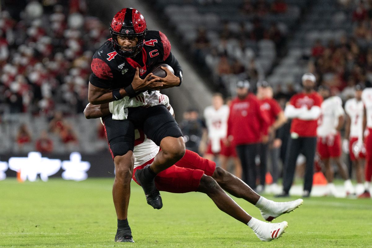 San Diego State University quarterback Jayden Denegal (4) fights through a tackle during a PAC-12 football game against Fresno State, Saturday October 17, 2026 in San Diego, California. San Diego State University quarterback Jayden Denegal (4) fights through a tackle during a PAC-12 football game against Fresno State, Saturday October 17, 2026 in San Diego, California.