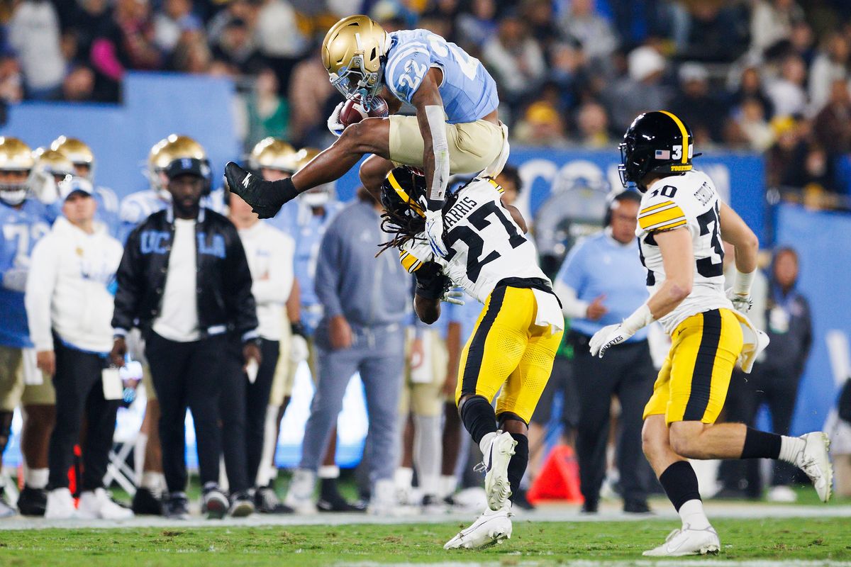 Keegan Jones #22 of the UCLA Bruins hurdles Jermari Harris #27 of the Iowa Hawkeyes during the first half game against Iowa Hawkeyes at Rose Bowl Stadium on November 8, 2024 in Pasadena, California.