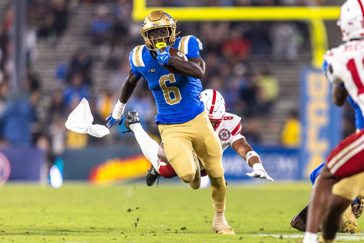 UCLA Bruins running back Anthony Woods (6) runs the ball while getting jumped on from behind as towel flys out of back pocket during the game against Nebraska Cornhuskers at Rose Bowl Stadium on November 8, 2025 in Pasadena, California. 