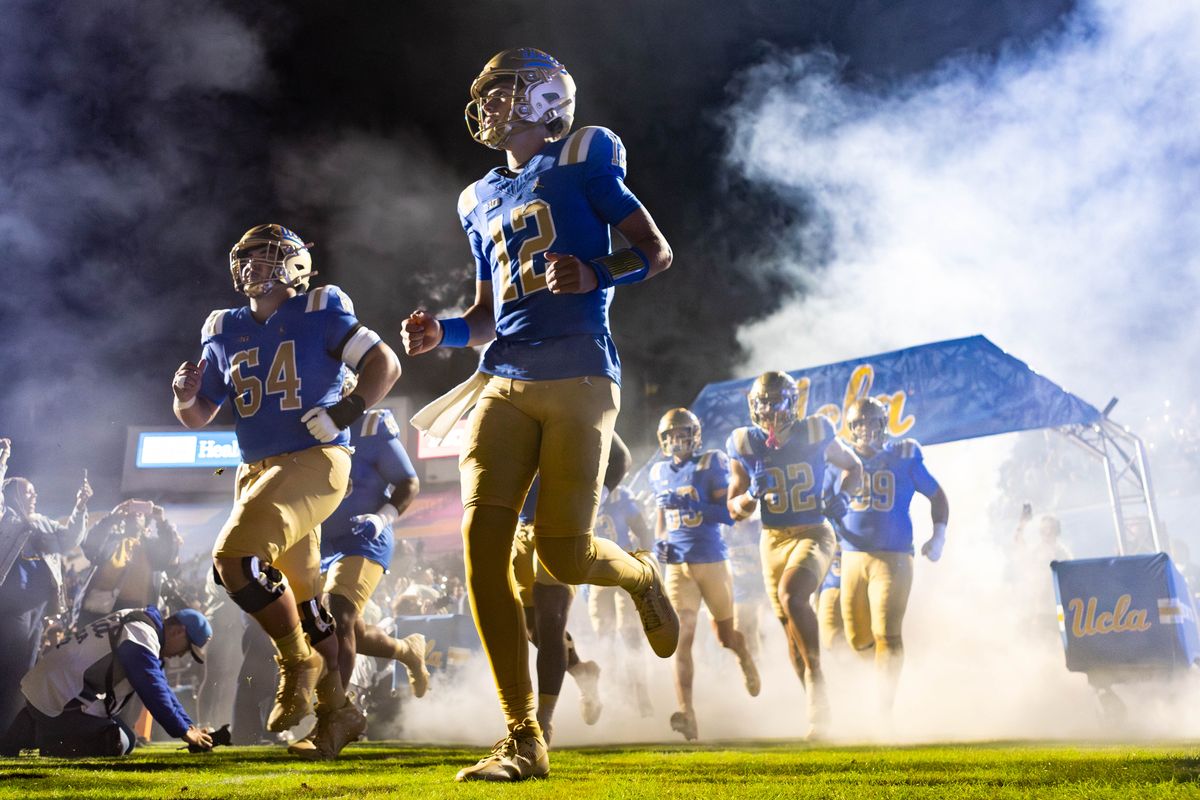 UCLA Bruins quarterback Luke Duncan (12) runs out of the smoke before the game against Washington Huskies at Rose Bowl Stadium on November 22, 2025 in Pasadena, California. 