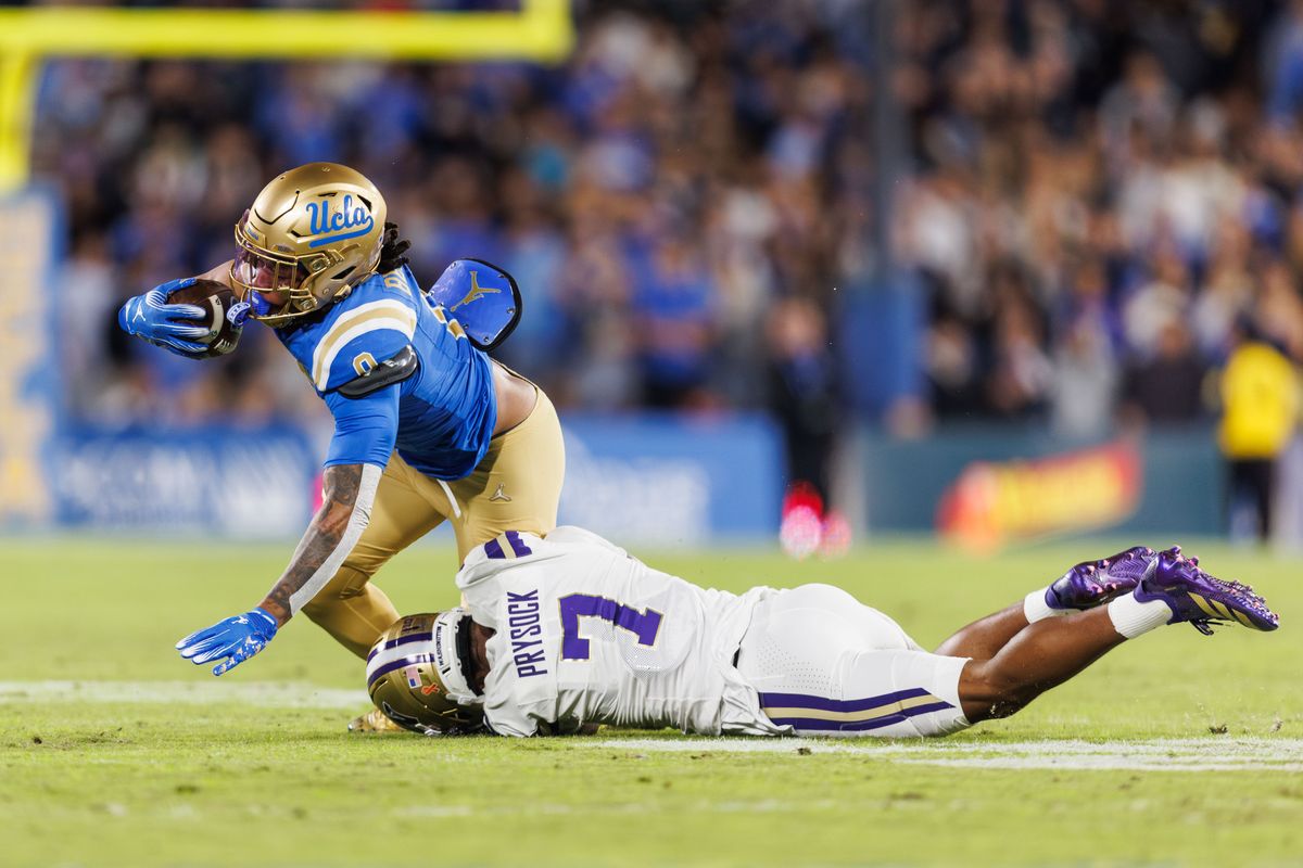 UCLA Bruins running back Jalen Berger (0) gets tackled by Washington Huskies cornerback Ephesians Prysock (7) during the game against Washington Huskies at Rose Bowl Stadium on November 22, 2025 in Pasadena, California. 