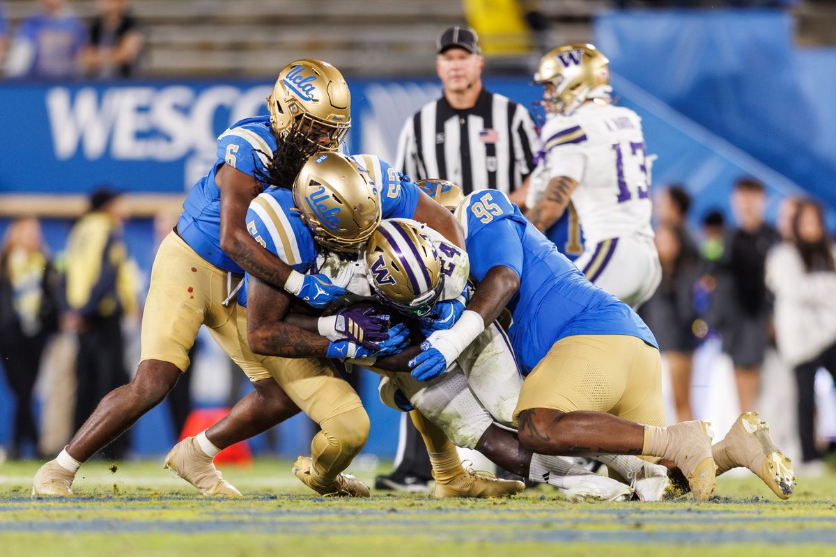 UCLA Bruins defensive lineman Jalen Hargrove (95) tackles Washington Huskies running back Adam Mohammed (24) during the game against Washington Huskies at Rose Bowl Stadium on November 22, 2025 in Pasadena, California. 