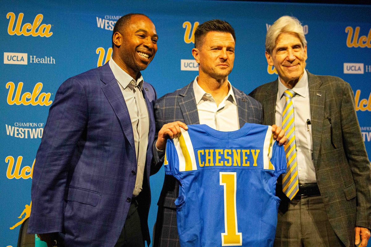 UCLA chancellor Julio Frenk, athletic director Martin Jarmonds and new football head coach Bob Chesney pose with Chesney's new UCLA jersey at the introductory press conference for Bob Chesney at Luskin Conference Center Tuesday, December 9, 2025 in Los Angeles. 