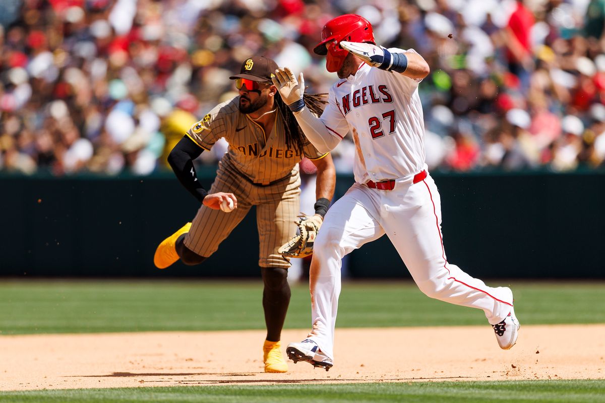 Mike Trout #27 of the Los Angeles Angels runs past Fernando Tatis Jr. #23 of the San Diego Padres as he fields the ball during the game at Angel Stadium of Anaheim on April 19, 2026 in Anaheim, California.