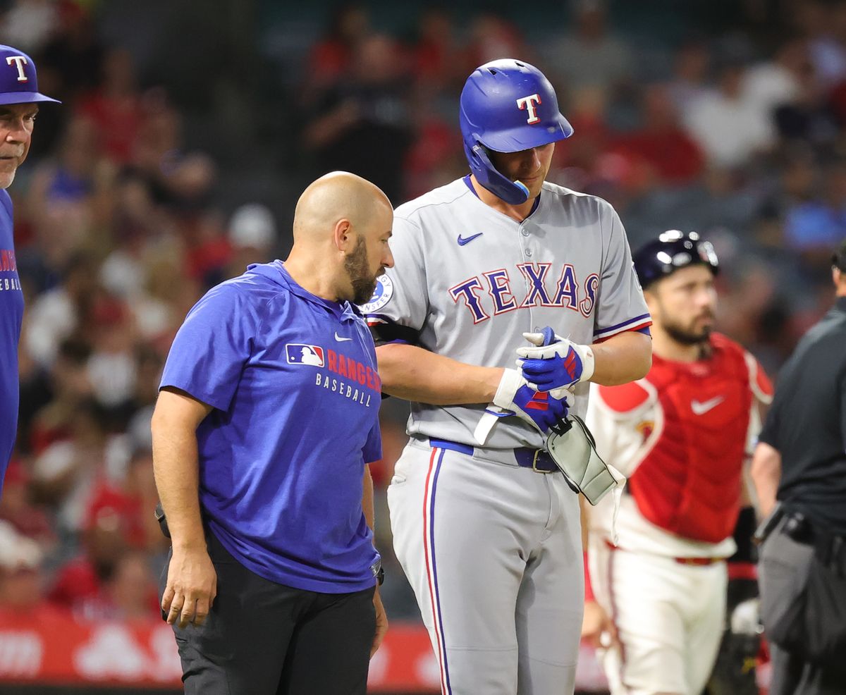 #5 Corey Seager is helped to first base after getting hit by a pitch against the Los Angeles Angels on July 9, 2025 in Anaheim, CA.
