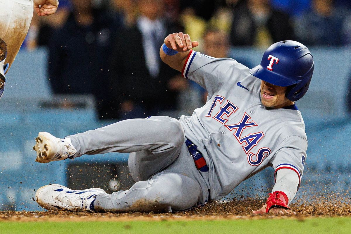 Sam Haggerty #0 of the Texas Rangers slides into home plate during an MLB game against the Los Angeles Dodgers at Dodger Stadium on April 10, 2026 in Los Angeles, California.