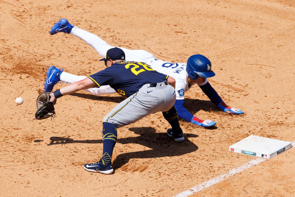 Hyeseong Kim #6 of the Los Angeles Dodgers slides back to first base to avoid the tag by Andrew Vaughn #28 of the Milwaukee Brewers during the game at Dodger Stadium on July 20, 2025 in Los Angeles, California. 