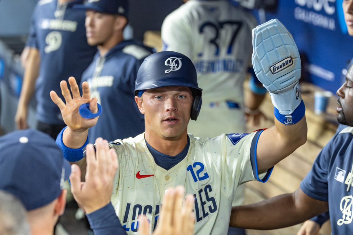 Alex Call #12 of the Los Angeles Dodgers gets high-fives in the dugout after scoring the lone Dodgers run during an MLB game against the Arizona Diamondbacks at Dodger Stadium on August 30, 2025 in Los Angeles, California.