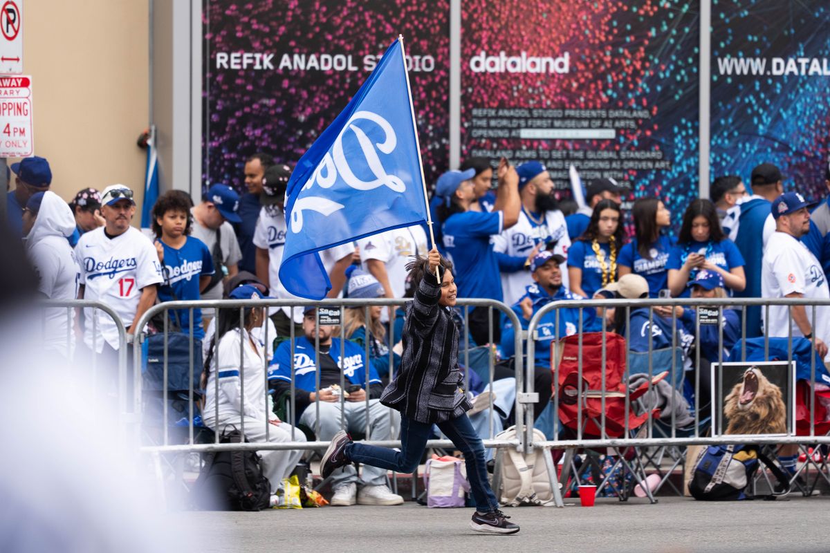 LOS ANGELES, Calif. — Nov. 3, 2025 — A young fan runs down the street waving a Dodgers flag during the team’s championship parade on Monday. LOS ANGELES, Calif. — Nov. 3, 2025 — A young fan runs down the street waving a Dodgers flag during the team’s championship parade on Monday.