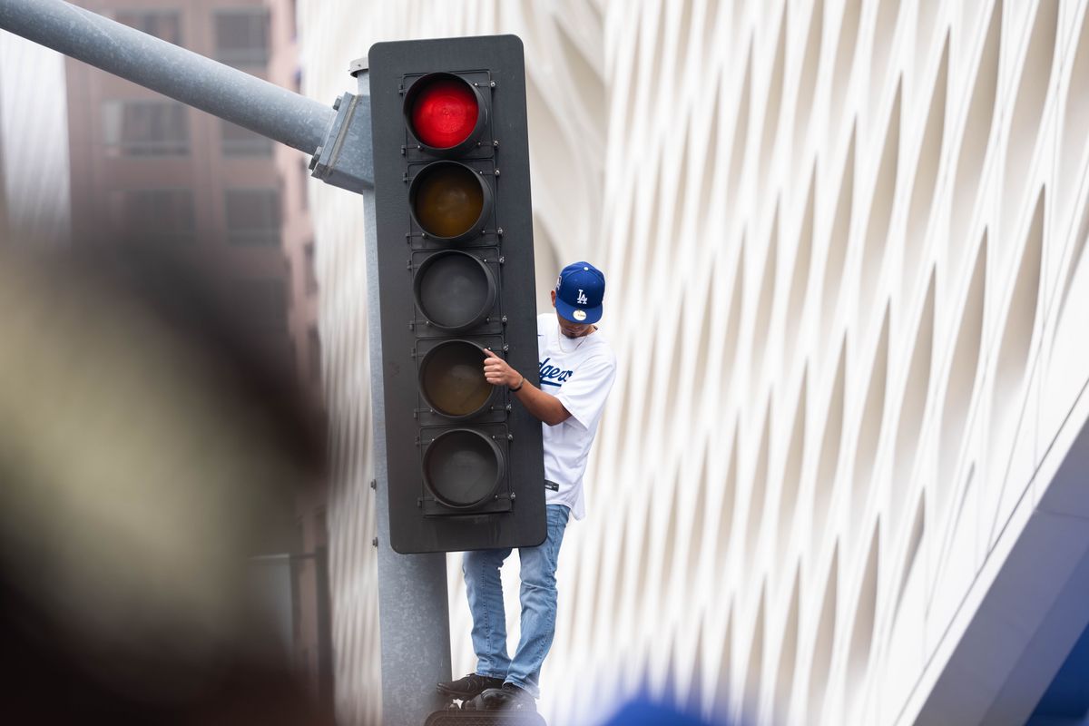 LOS ANGELES, Calif. — Nov. 3, 2025 — A Dodgers fan climbs a traffic light during the team’s championship parade on Monday. LOS ANGELES, Calif. — Nov. 3, 2025 — A Dodgers fan climbs a traffic light during the team’s championship parade on Monday.