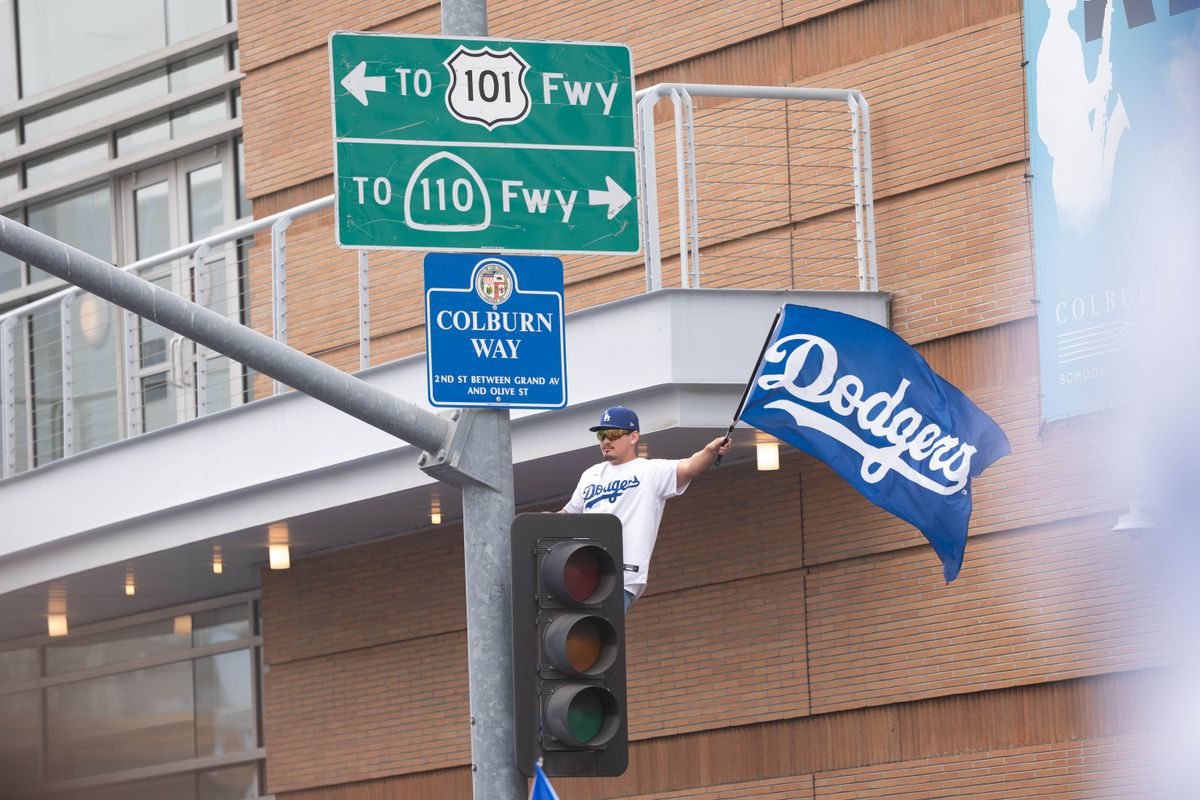 LOS ANGELES, Calif. — Nov. 3, 2025 — A Dodgers fan waves a Dodgers flag while sitting atop a traffic light during the team’s championship parade on Monday. LOS ANGELES, Calif. — Nov. 3, 2025 — A Dodgers fan waves a Dodgers flag while sitting atop a traffic light during the team’s championship parade on Monday.