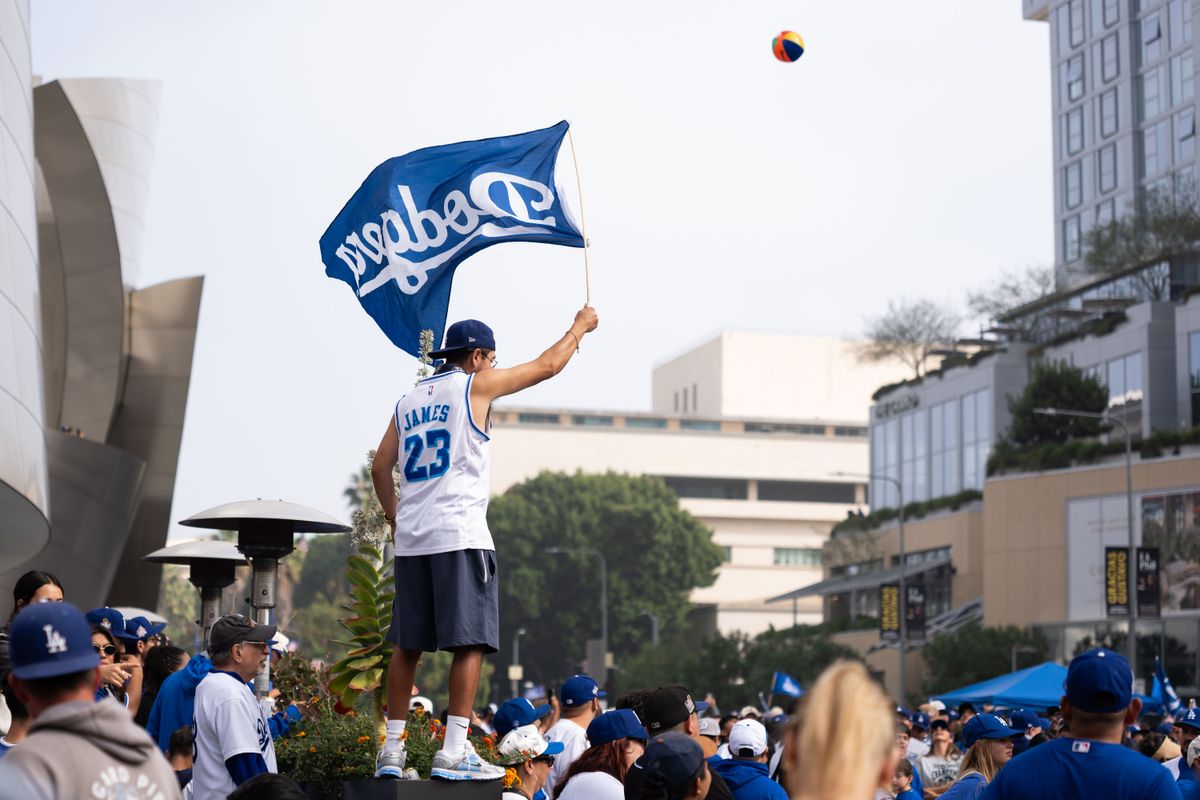 LOS ANGELES, Calif. — Nov. 3, 2025 — A Dodgers fan waves a Dodgers flag while standing atop a staircase during the team’s championship parade on Monday. LOS ANGELES, Calif. — Nov. 3, 2025 — A Dodgers fan waves a Dodgers flag while standing atop a staircase during the team’s championship parade on Monday.