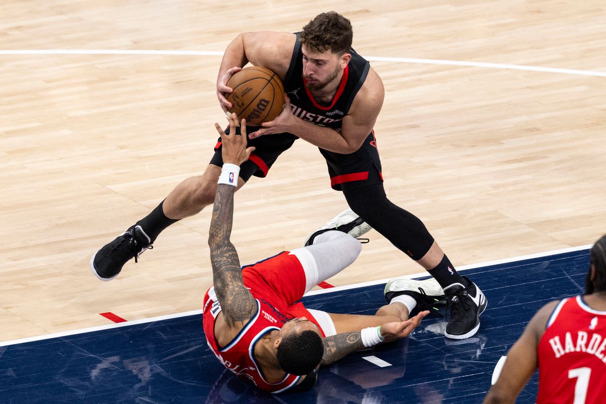 Alperen Sengun #28 of the Houston Rockets steps over John Collins #20 of the LA Clippers during an NBA basketball game, Tuesday December 23, 2025 in Inglewood, Calif.