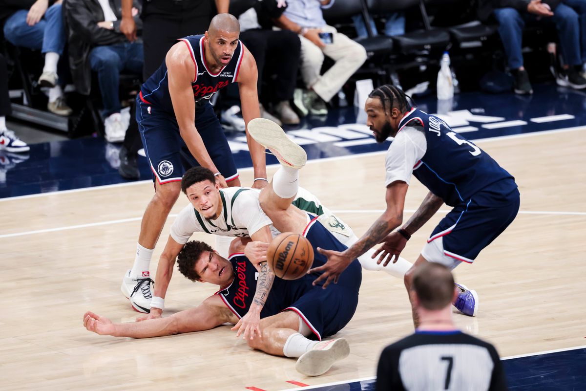 Brook Lopez #11 of the LA Clippers and Ryan Rollins #13 of the Milwaukee Bucks fight for a loose ball on the floor during an NBA basketball game, 2026 in Inglewood, Calif.