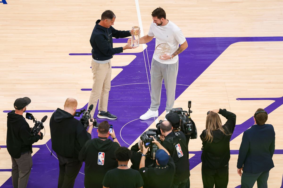 Luka Doncic #77 of the Los Angeles Lakers is presented with the trophy for his NBA scoring title by Lakers Vice President and General Manager Rob Pelinka during an NBA Playoffs basketball game against the Houston Rockets, Tuesday April 21, 2026 in Los Angeles, Calif.