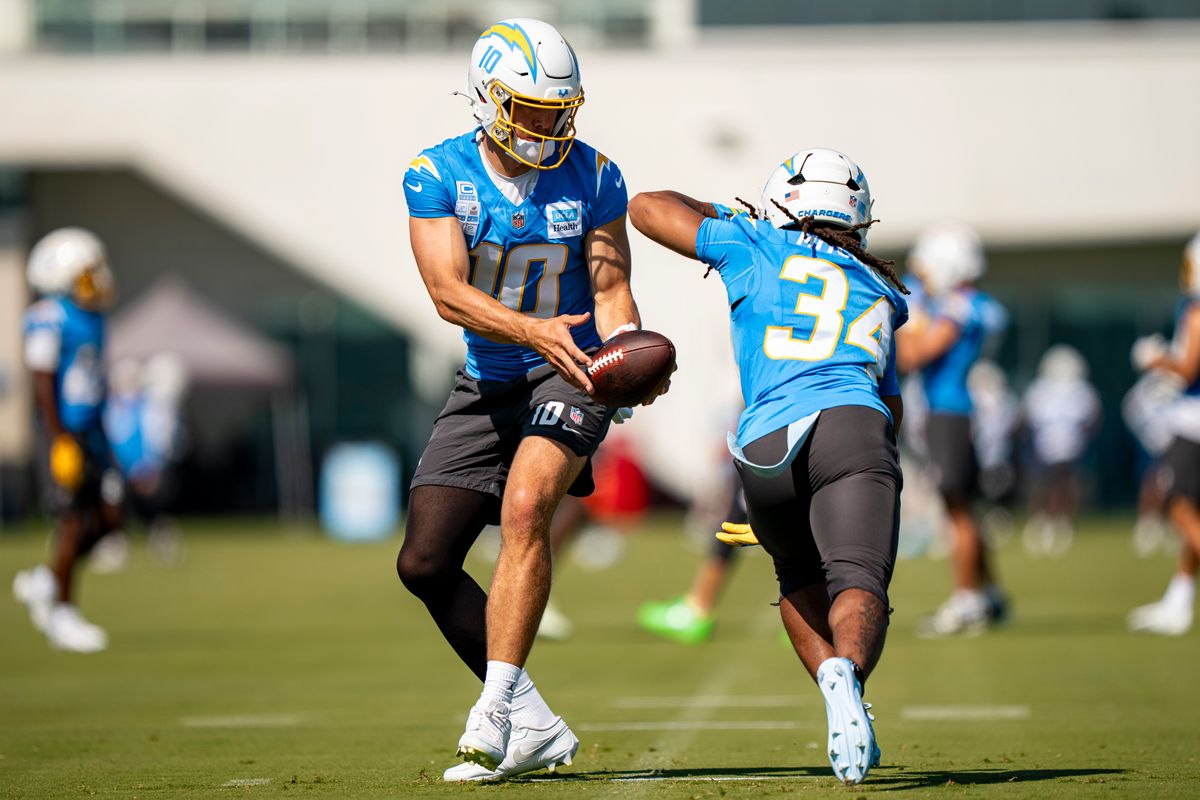 Los Angeles Chargers quarterback Justin Herbert (10) handing the ball off to running back Keaton Mitchell (34) during Chargers training camp at The Bolt on Friday, July 31th in El Segundo, CA. Los Angeles Chargers quarterback Justin Herbert (10) handing the ball off to running back Keaton Mitchell (34) during Chargers training camp at The Bolt on Friday, July 31th in El Segundo, CA.