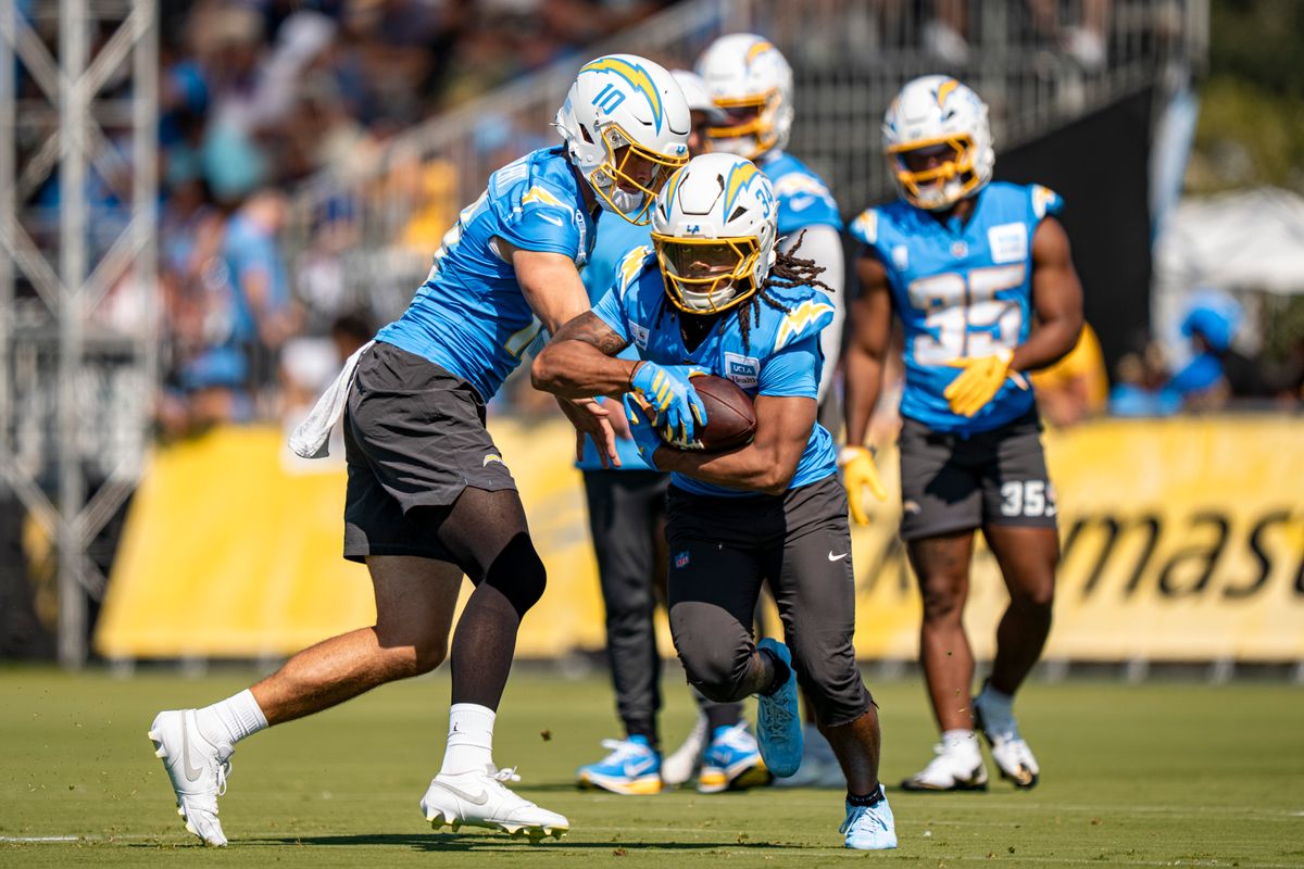 Los Angeles Chargers quarterback Justin Herbert (10) handing the ball off to running back Keaton Mitchell (34) during Chargers training camp at The Bolt on Friday, July 31th in El Segundo, CA. Los Angeles Chargers quarterback Justin Herbert (10) handing the ball off to running back Keaton Mitchell (34) during Chargers training camp at The Bolt on Friday, July 31th in El Segundo, CA.