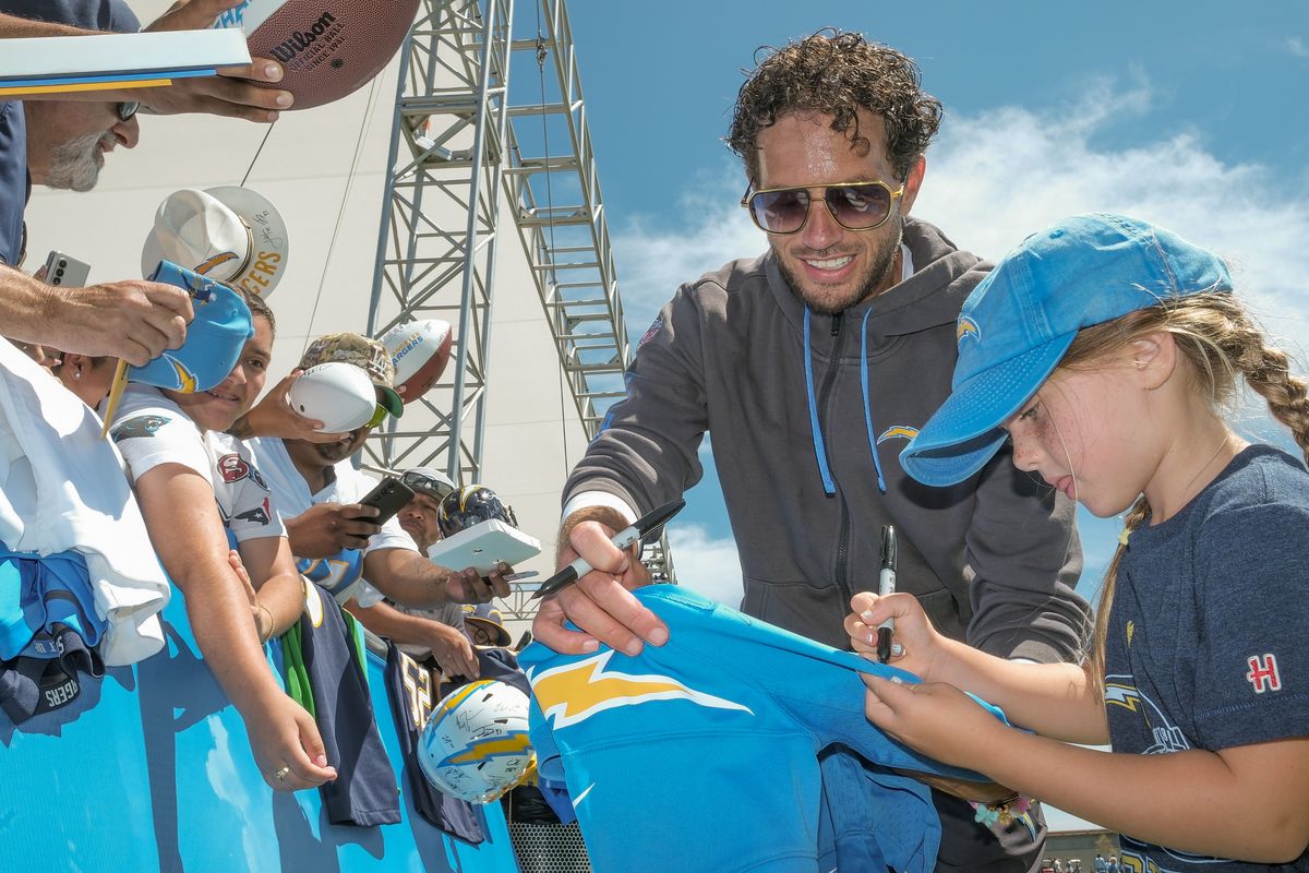 Los Angeles Chargers offensive coordinator Mike McDaniels signing autographs with his daughter for fans during a joint Chargers and 49ers training camp at The Bolt on Saturday, August 18th in El Segundo, CA. Los Angeles Chargers offensive coordinator Mike McDaniels signing autographs with his daughter for fans during a joint Chargers and 49ers training camp at The Bolt on Saturday, August 18th in El Segundo, CA.