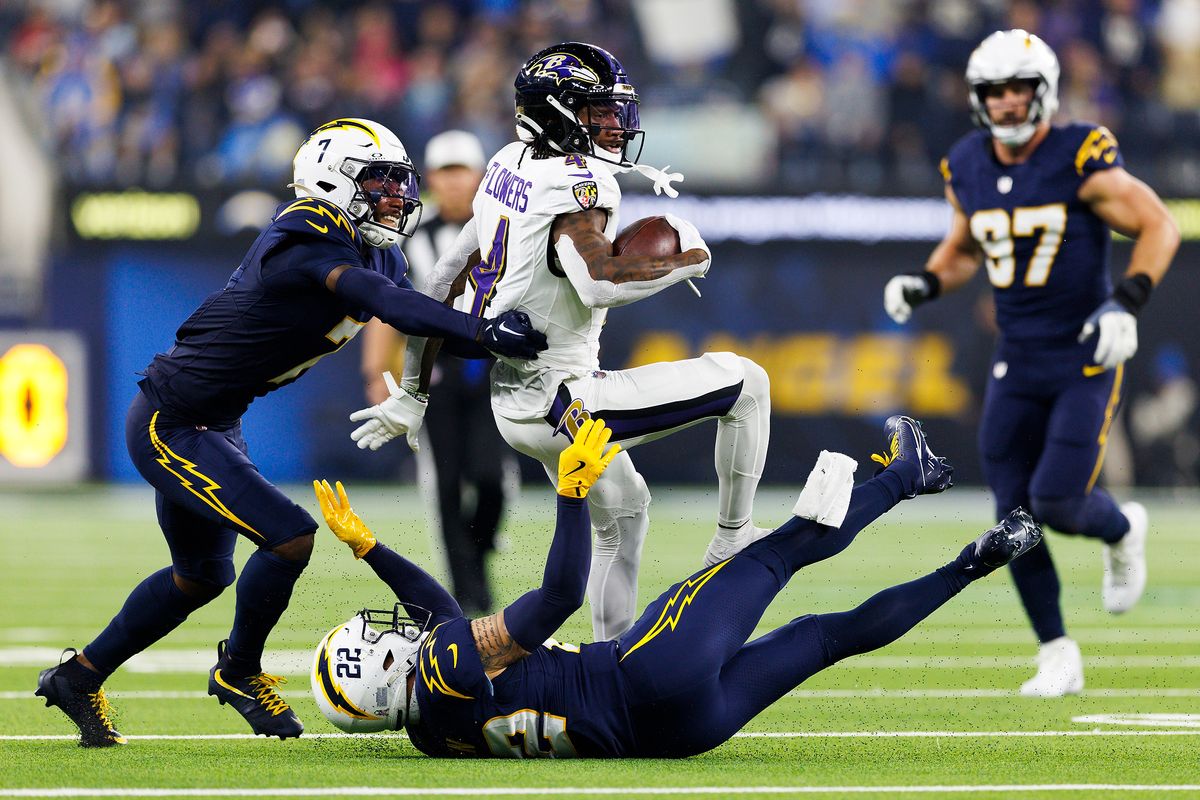 Zay Flowers #4 of the Baltimore Ravens is tackled by Kristian Fulton #7 of the Los Angeles Chargers and Elijah Molden #22 of the Los Angeles Chargers during the second half at SoFi Stadium on November 25, 2024 in Inglewood, California.