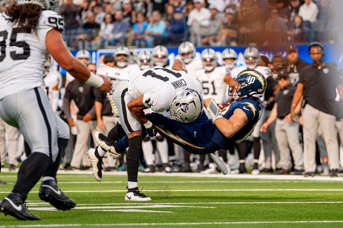 Las Vegas Raiders safety, Jeremy Chinn (11) tackles Justin Herbert (10) during an NFL football game against the Los Angeles Chargers on November 30, 2025 in Los Angeles, CA.
