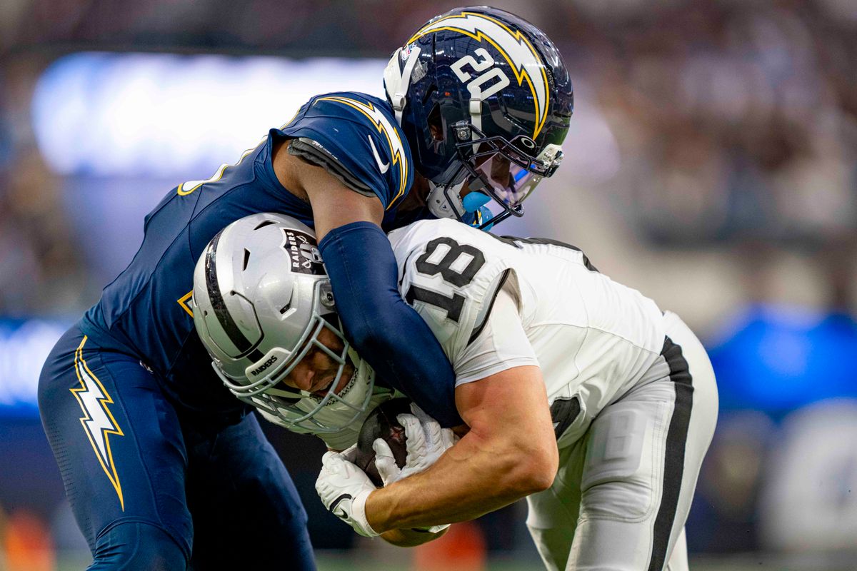 Los Angeles Chargers safety, Cam Hart (20) tackles Jack Bech (18) during an NFL football game against the Las Vegas Raiders on November 30, 2025 in Los Angeles, CA.