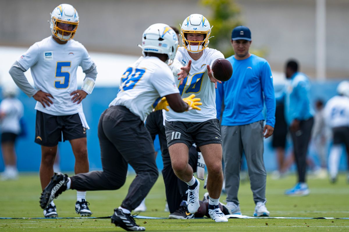 Los Angeles Chargers quarterback Justin Herbert (10) tosses the ball off to running back Kimani Vidal (28) during Chargers organized team activities at the Bolt on Tuesday, June 2nd in El Segundo, CA. Los Angeles Chargers quarterback Justin Herbert (10) tosses the ball off to running back Kimani Vidal (28) during Chargers organized team activities at the Bolt on Tuesday, June 2nd in El Segundo, CA.
