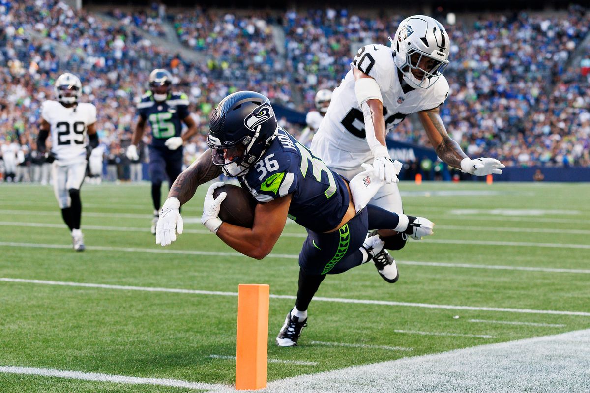 George Holani #36 of the Seattle Seahawks dives for the end zone against Isaiah Pola-Mao #20 of the Las Vegas Raiders during the first half at Lumen Field on August 7, 2025 in Seattle, Washington.