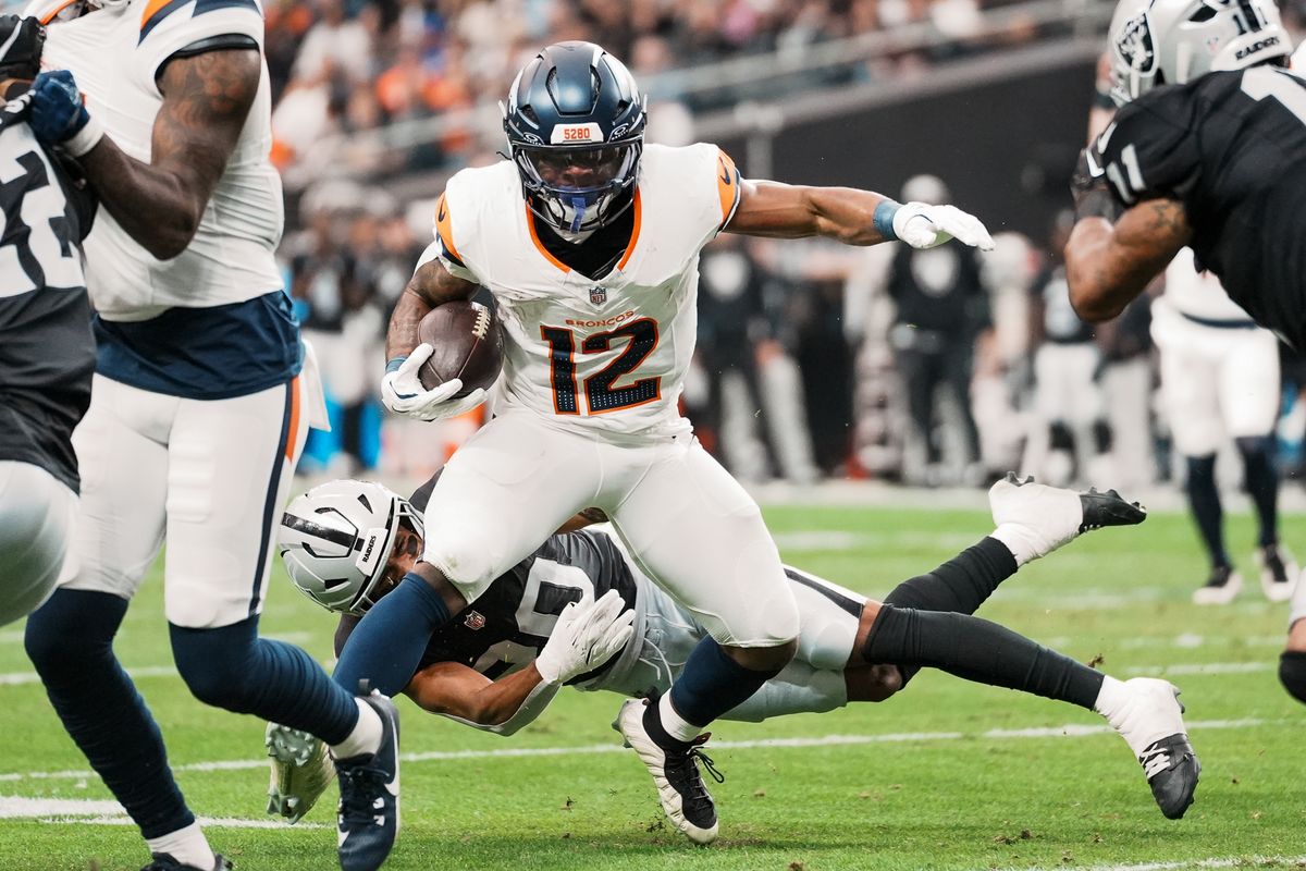 Broncos running back RJ Harvey (12) dodges a tackle from Raiders safety Isaiah Pola-Mao (20) during first quarter  of NFL game against the Raiders on Sunday, Dec. 7, 2025 at Allegiant Stadium in Las Vegas.