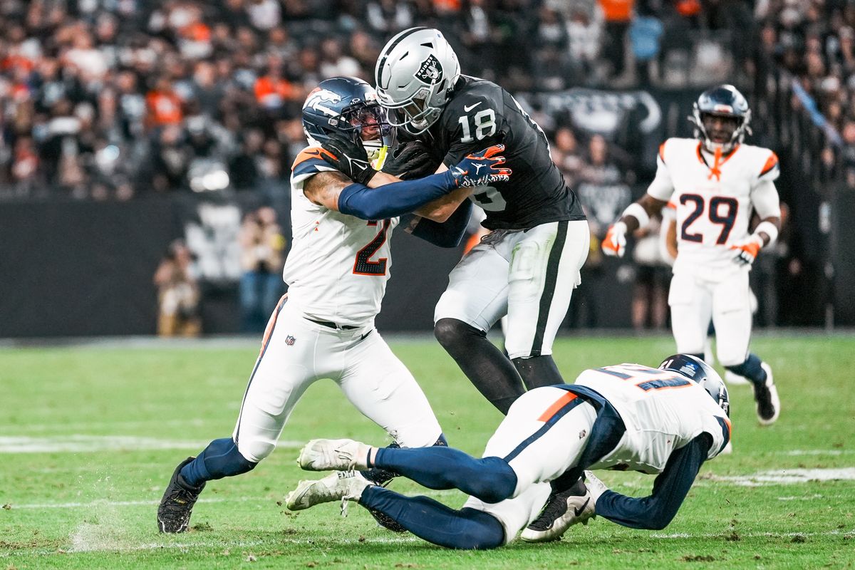 Raiders wide receiver Jack Bech (18) is tackled by Broncos cornerback Pat Surtain II (2) and Riley Moss (21) during fourth quarter of NFL game against the Broncos Sunday, Dec. 7, 2025 at Allegiant Stadium in Las Vegas.