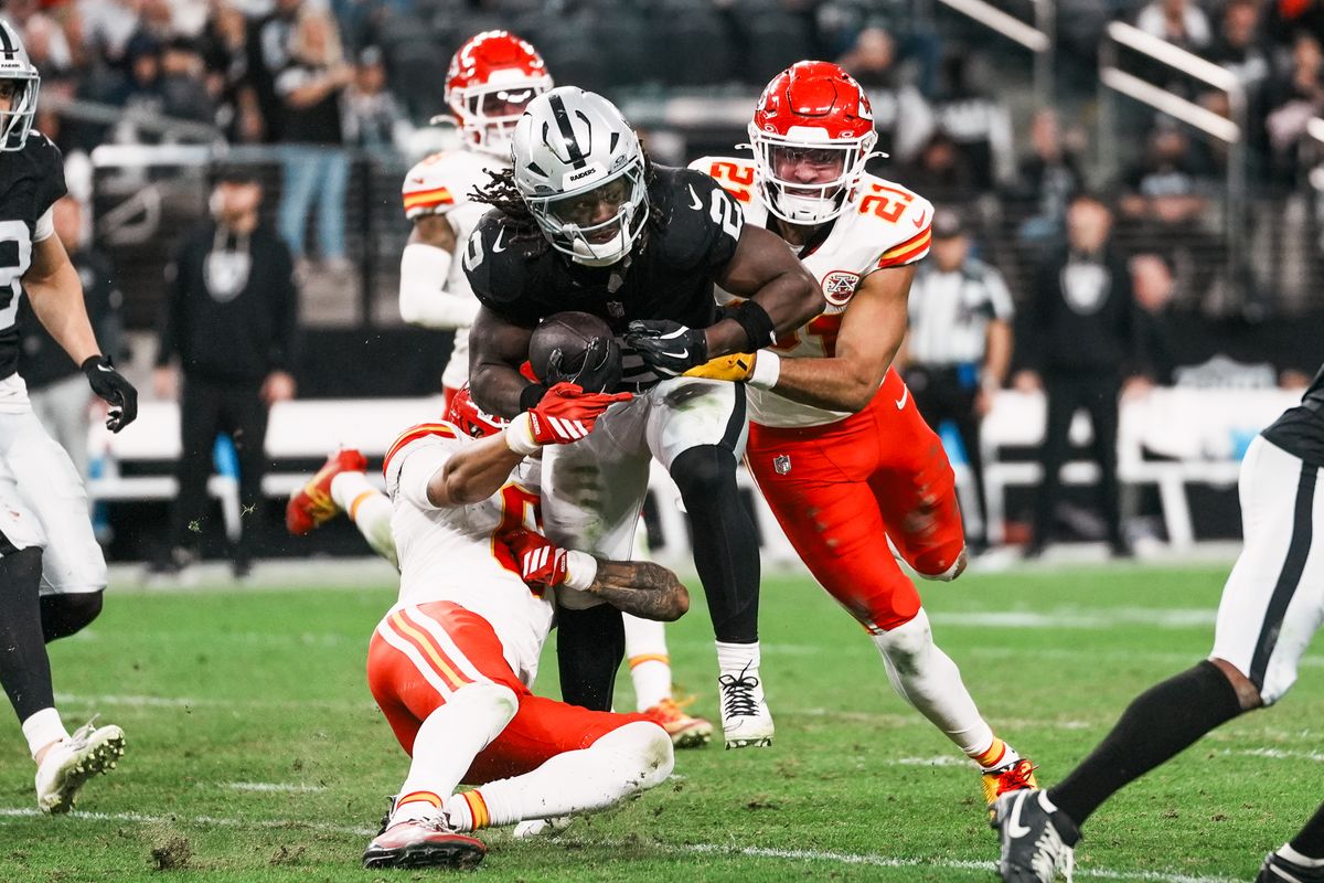 Raiders running back Ashton Jeanty (2) attempts to run the ball through Chiefs defensive back Jaden Hicks (21) and safety Bryan Cook (6)  during second half of NFL game against Chiefs on Sunday, January 4, 2026 at Allegiant Stadium in Las Vegas.