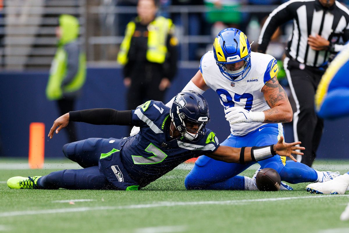 Geno Smith #7 of the Seattle Seahawks and Michael Hoecht #97 of the Los Angeles Rams dive for a loose ball during the first half at Lumen Field on November 3, 2024 in Seattle, Washington. Geno Smith #7 of the Seattle Seahawks and Michael Hoecht #97 of the Los Angeles Rams dive for a loose ball during the first half at Lumen Field on November 3, 2024 in Seattle, Washington.