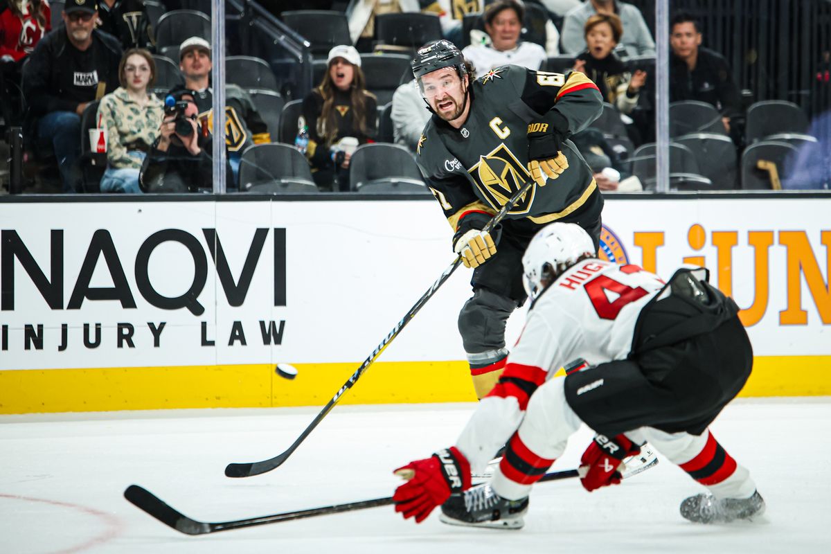 Vegas Golden Knights RW Mark Stone (61) passes the puck over New Jersey Devils D Luke Hughes (43) during the second period of an NHL game on Sunday March 02, 2025, at T-Mobile Arena. 
