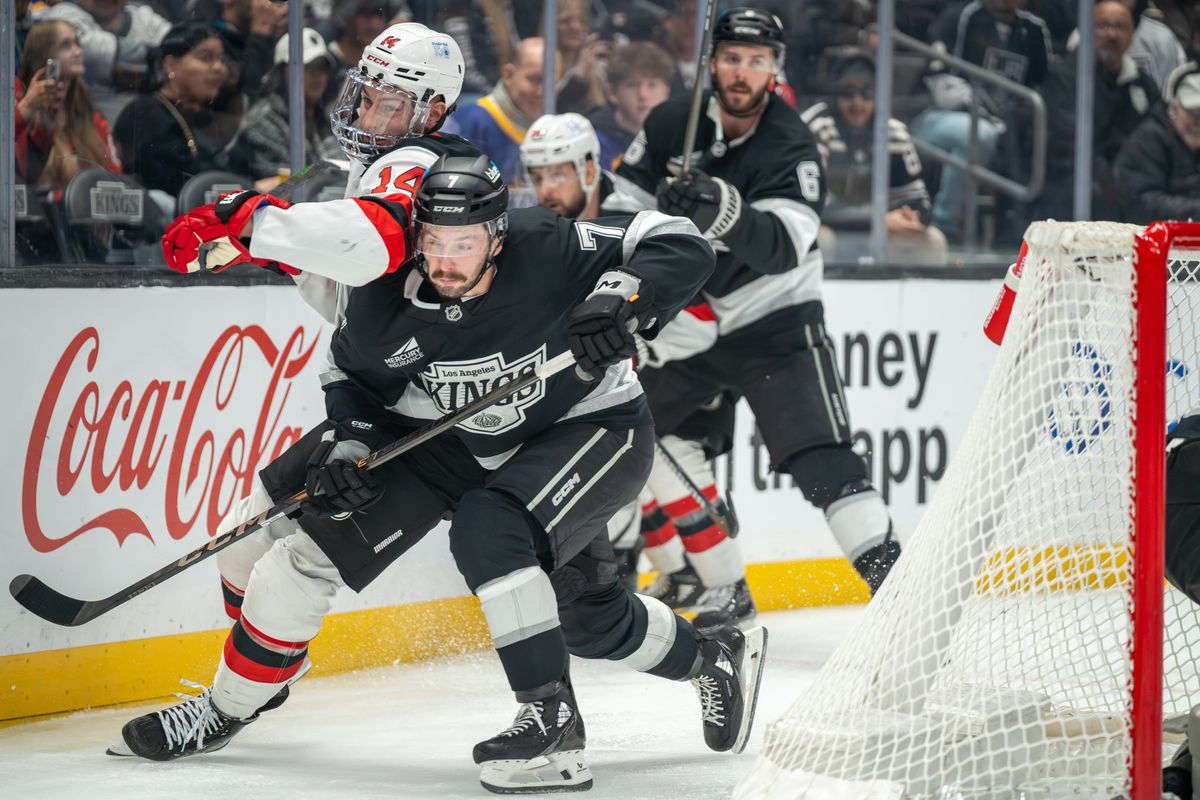 Kyle Burroughs #7 of the Los Angeles Kings battles Nathan Bastian #14 of the New Jersey Devils along the boards during the second period at Crypto.com Arena on January 1, 2025, in Los Angeles, California.