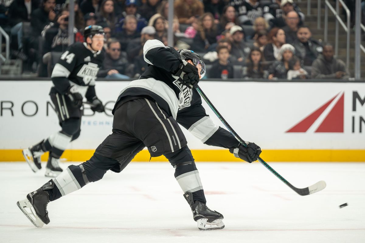 Mikey Anderson #44 of the Los Angeles Kings dumps the puck down the ice during the second period against the New Jersey Devils at Crypto.com Arena on January 1, 2025, in Los Angeles, California.