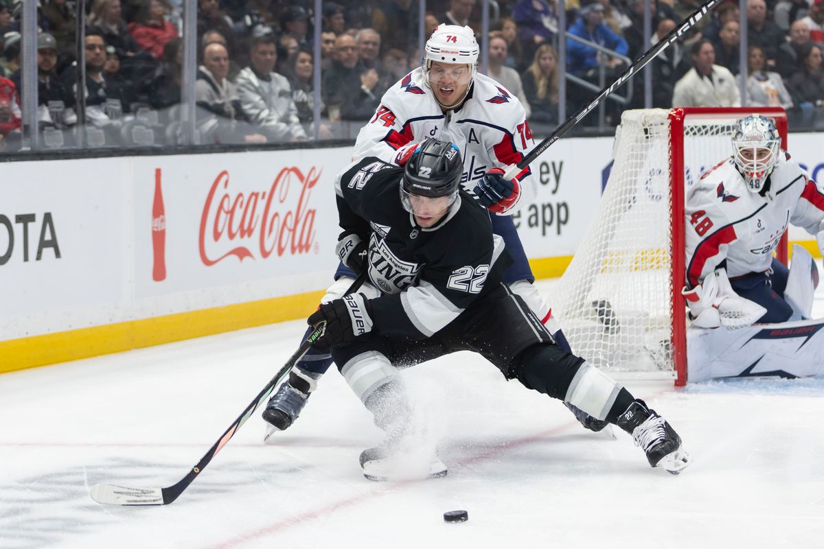 Left wing Kevin Fiala #22 of the Los Angeles Kings reaches for the puck as defenseman John Carlson #74 of the Washington Capitals pushes him during an NHL hockey game, Tuesday December 2, 2025 in Los Angeles, Calif.