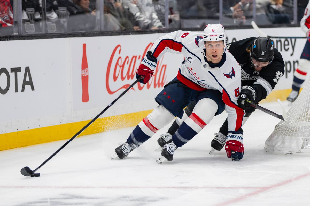 Defenseman Jakob Chychrun #6 of the Washington Capitals skates around the goal with the puck as right wing Adrian Kempe #9 of the Los Angeles Kings reaches for it during an NHL hockey game, Tuesday December 2, 2025 in Los Angeles, Calif.
