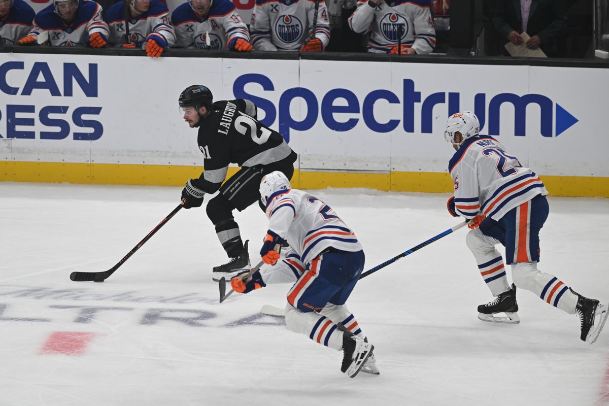 LA Kings center Scott Laughton (21) pushes the puck past two defenders during an NHL game between the Edmonton Oilers and the Los Angeles Kings on Saturday, April 11, 2026 at Crypto.com Arena in Los Angeles Calif