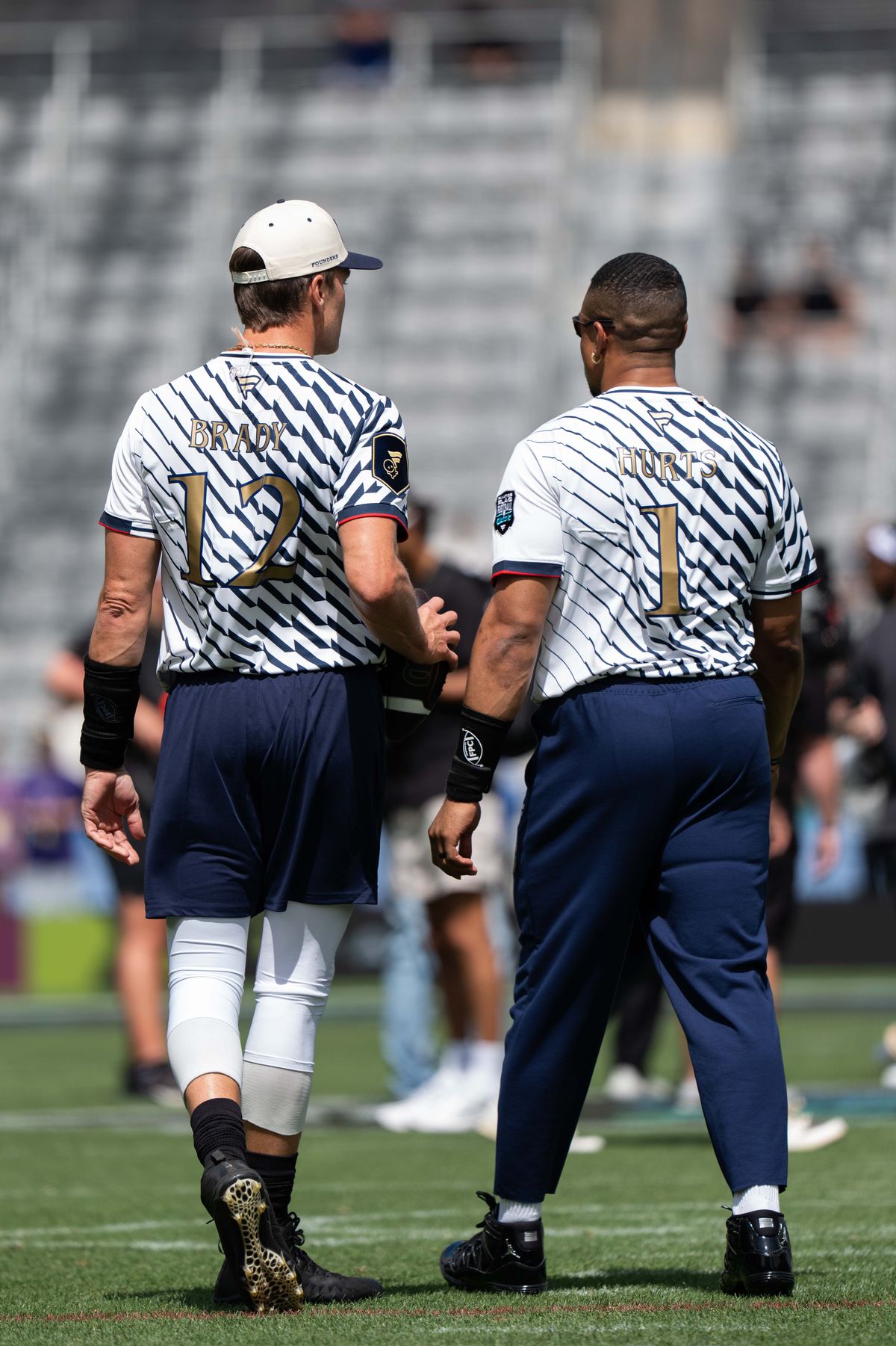 Founders quarterbacks Tom Brady (12) and Jalen Hurts (1) walk on the field during warmups ahead of the Fanatics Flag Football event, March 21, 2026, in Los Angeles. Founders quarterbacks Tom Brady (12) and Jalen Hurts (1) walk on the field during warmups ahead of the Fanatics Flag Football event, March 21, 2026, in Los Angeles.