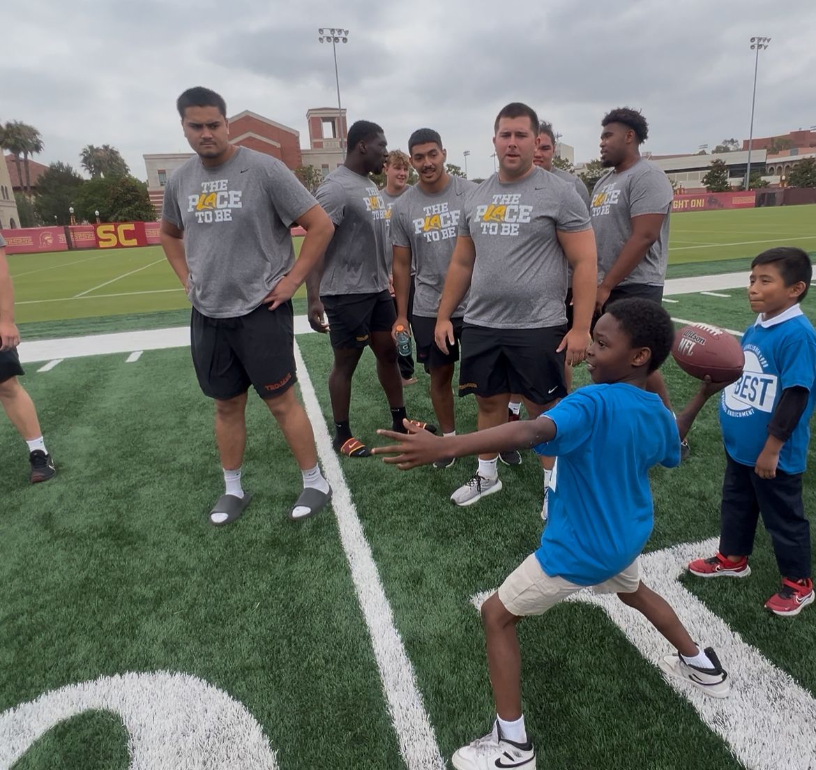 Players teach a young student how to be a quarterback.