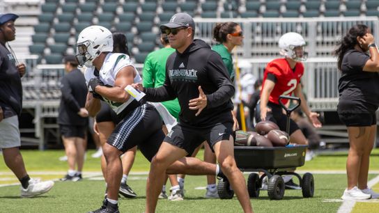 Fourth-year head coach Timmy Chang demonstrates a stance during a University of Hawai’i football practice.