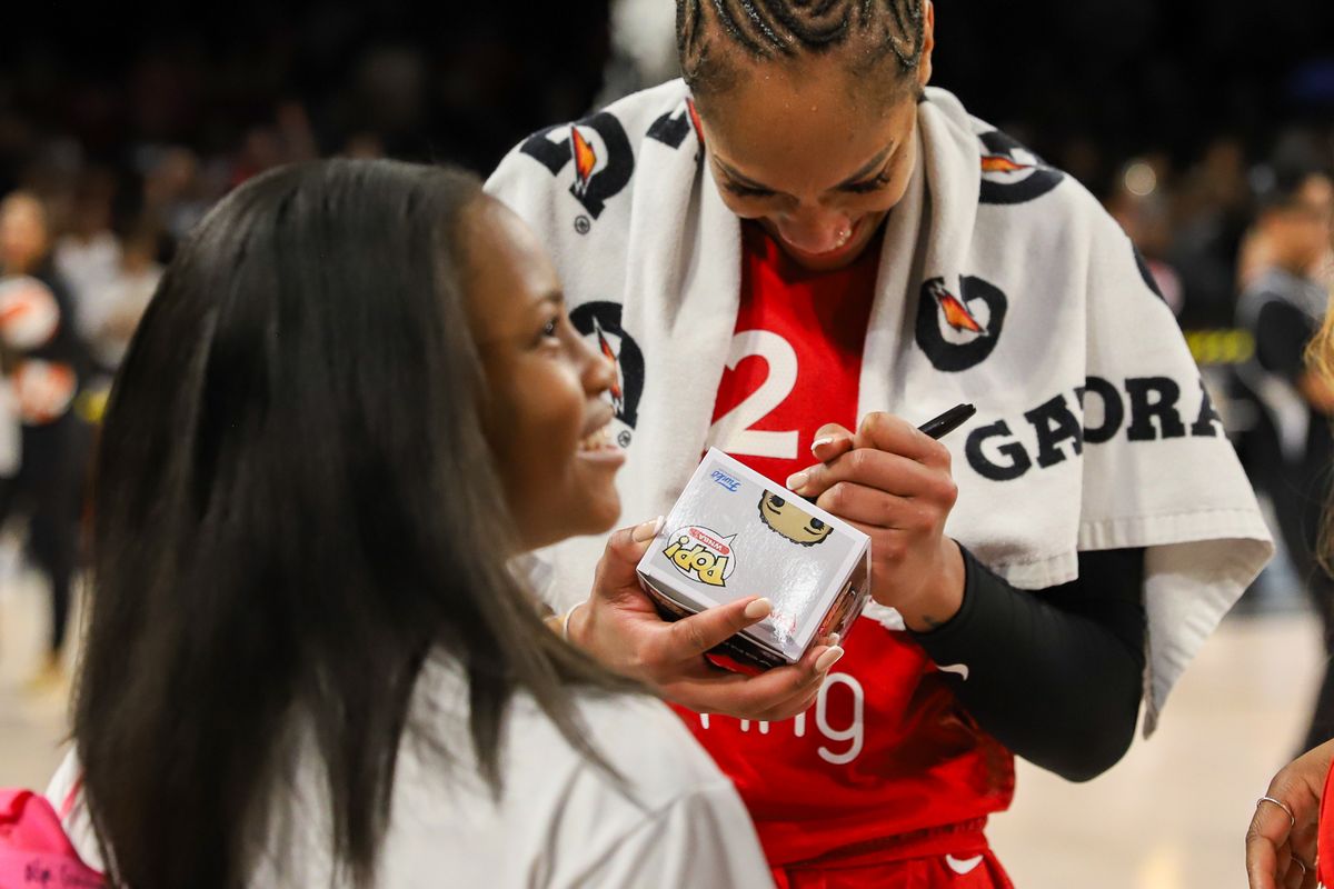 Las Vegas Aces center A’ja Wilson (22) signs her Funko Pop action figure for a young fan following WNBA game against Atlanta Dream on Tuesday July 22 ,2025 in Las Vegas.  